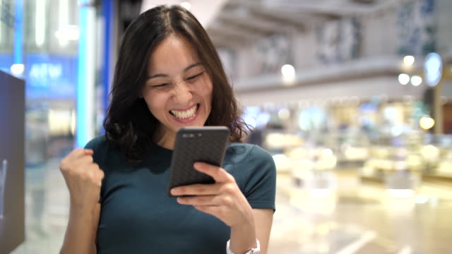 Asian woman using Smart phone Winning Concept celebrating success