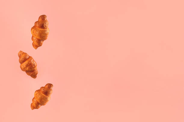 istock Croissants flying on pink background. Levitation scene. 1211359436
