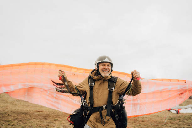 Take off time Photo of a smiling senior man ready for take off with his paraglider skydiving stock pictures, royalty-free photos & images