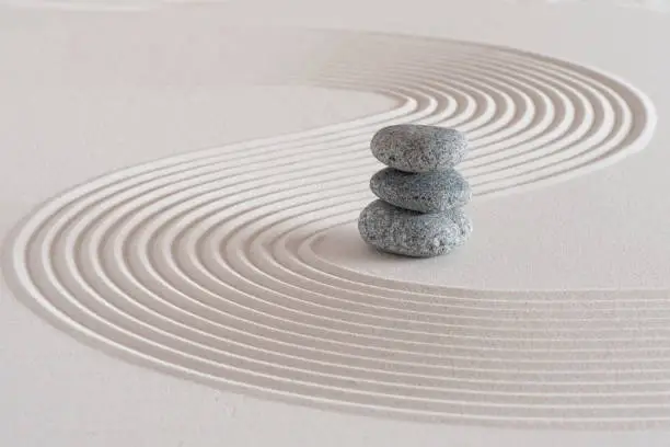 Photo of Japanese zen garden with stone in textured sand