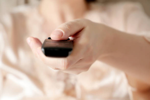 istock TV remote in a female hand close up 1211363646