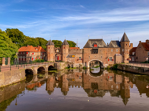 medieval Koppelpoort town wall and gate over the Eem river in the historical center of Amersfoort, Utrecht Province, The Netherlands during a beautiful summer day. People are walking on the streets and sidewalks in the city centre.