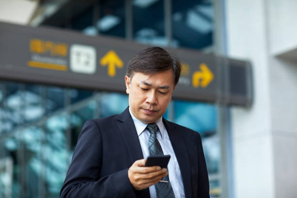 istock Mature entrepreneur using phone at airport 1211368234