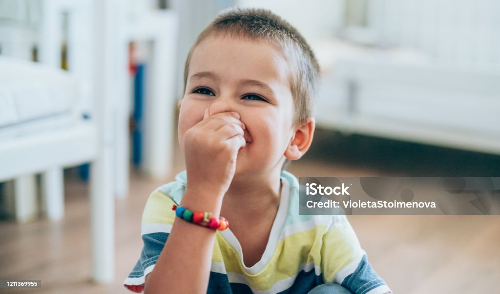 Little boy pinching his nose. Portrait of a cute little boy holding his nose for sign of bad smell. Child Stock Photo