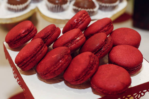 stylish red macaroons, candy bar with sweets at luxury wedding reception. catering at restaurant. cupcakes  macarons on table. space for text