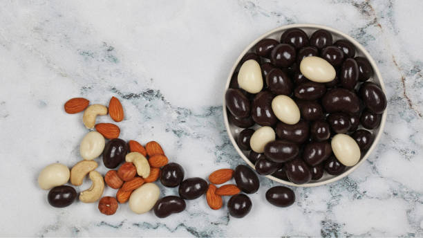 Raw and chocolate covered nuts on gray marble background