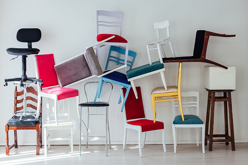 clutter of many different chairs standing in the white room