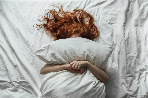 Red-haired little girl wakes up in the morning in her crib Red-haired little girl wakes up in the morning in her crib with white bed linen. hair on pillow stock pictures, royalty-free photos & images