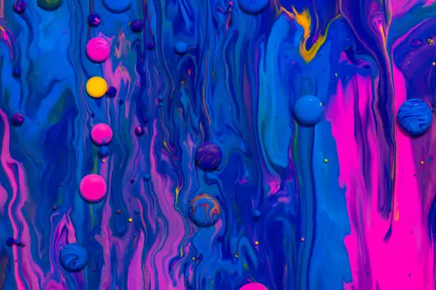 Acrylic paint balls abstract texture. Pink, blue and yellow liquids mix. Creative multicolor background. Bright colors fluid, flowing wallpaper design. Mixed pigments blue backdrop