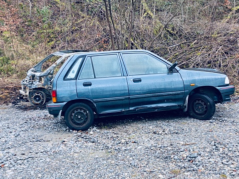 Old car left behind and another one burnt in the background