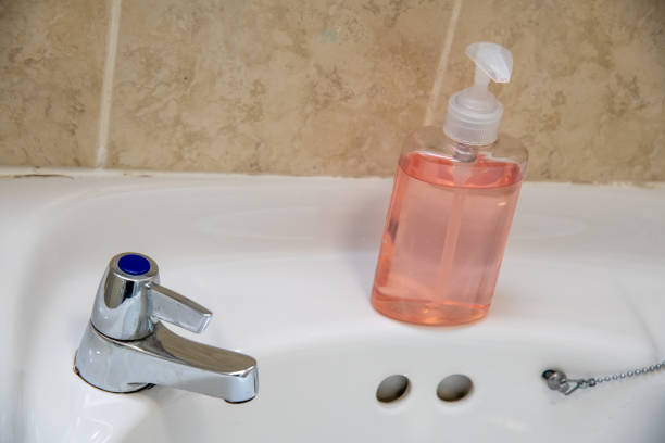 Clear pink hand sanitizer in a clear pump bottle isolated. Hand sanitizer is used for killing germs, bacteria and viruses, some of which can cause coronavirus COVID-19 H1N1 flu or swine flu.