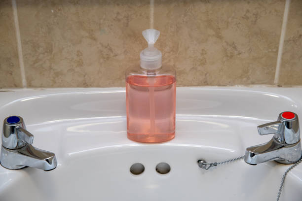 Soap container filled with purple foam fixed to green tile at wall in bathroom