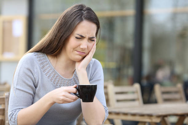 istock Woman suffering from tooth ache holding coffee mug on a terrace 1211384520