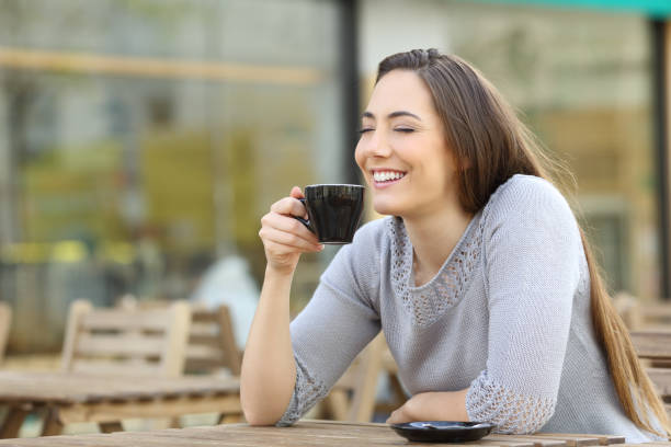 istock Satisfied woman smelling her coffee on a cafe terrace 1211384780