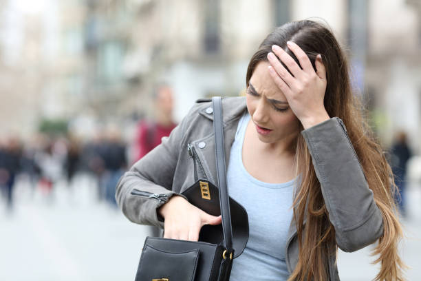 worried woman looking inside her bag on street - woman reaching into handbag imagens e fotografias de stock