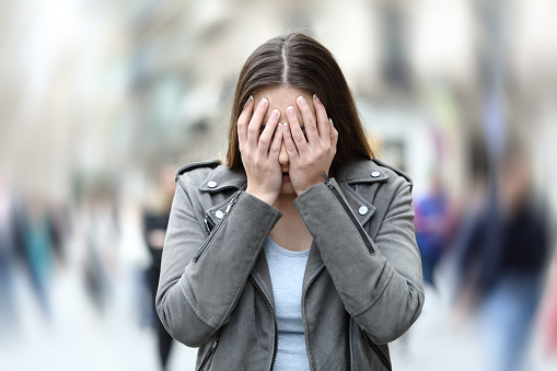 Front view of a woman suffering social anxiety attack on city street