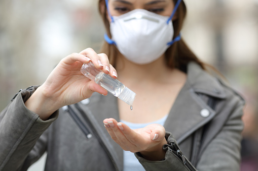 Woman with mask using hand sanitizer preventing contagion
