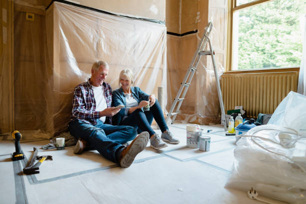 Couple Sitting Relaxing Senior couple sitting down taking a break on mobile while drinking tea. two heads are better than one stock pictures, royalty-free photos & images