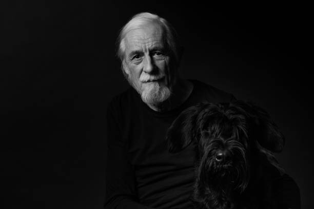 schwarz und weiß low key studio porträt von alten mann und seinem hund - portrait black and white senior men wisdom stock-fotos und bilder