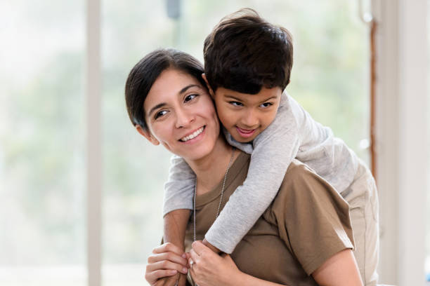 istock Little boy rides piggy back on his mom's back 1211388272