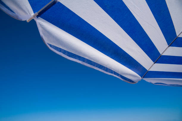 istock Blue and white beach umbrella against blue sky 1211389060