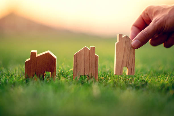 hand of woman choosing mini wood house model on green grass, planning buy real estate, eco house icon concept. - house human hand choice real estate imagens e fotografias de stock
