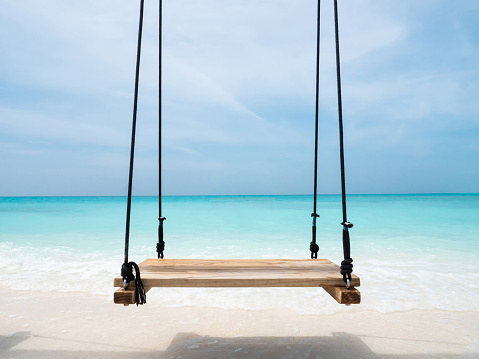 Happy woman relaxing in hammock during summer day on the beach. Copy space.