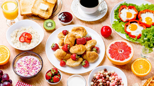 istock Continental breakfast with cereal, fried eggs, croissants, fruits and drinks on textured table, copy space. Table top with various healthy snacks and foods on rustic background 1211394660