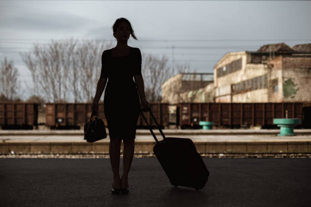 istock Young woman pulling a suitcase at the train station 1211395207