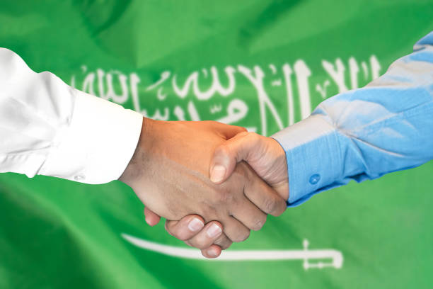 Business handshake on Saudi Arabia flag background. Men shaking hands and Saudi Arabia flag on background. Support concept