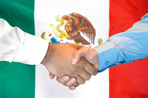 Business handshake on Mexico flag background. Men shaking hands and Mexico flag on background. Support concept