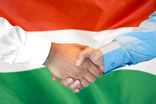 Business handshake on Hungary flag background. Men shaking hands and Hungary flag on background. Support concept