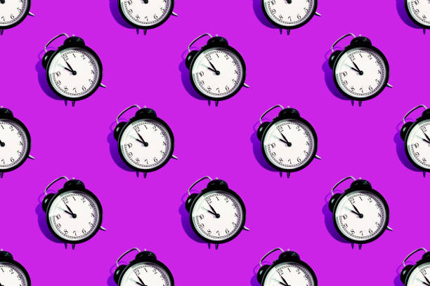 istock Many black classic style alarm clock isolated on pink background 1211397061