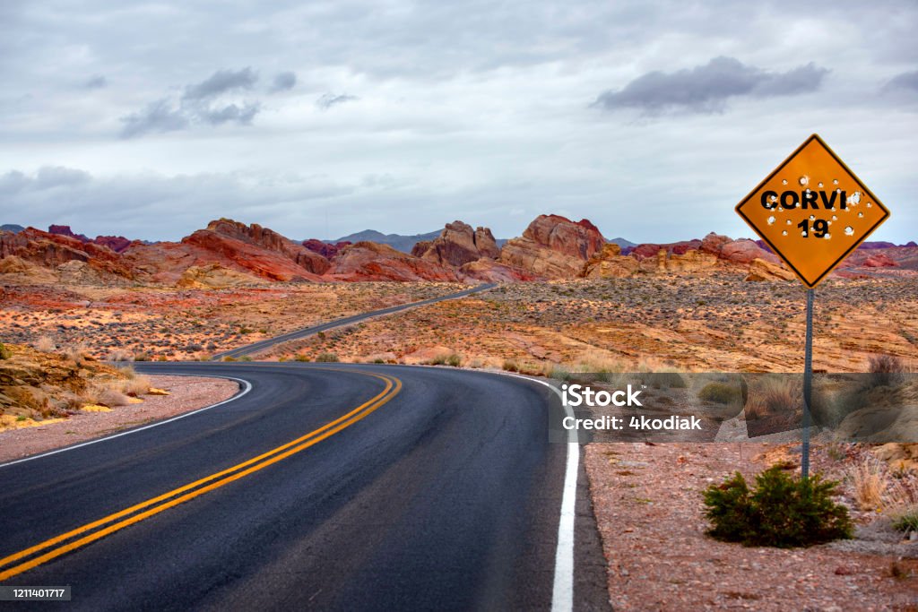 Desert road sign with CORVID 19 and bullets Corvis 19 road sign with bullets on desert area. Bullet Stock Photo