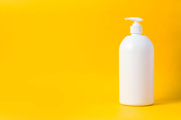 White bottle for cleaner or liquid soap on yellow background. Mock up for text or design