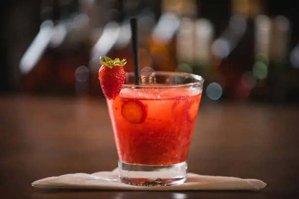 Strawberry caipirinha, decorated with cherry on a wooden table