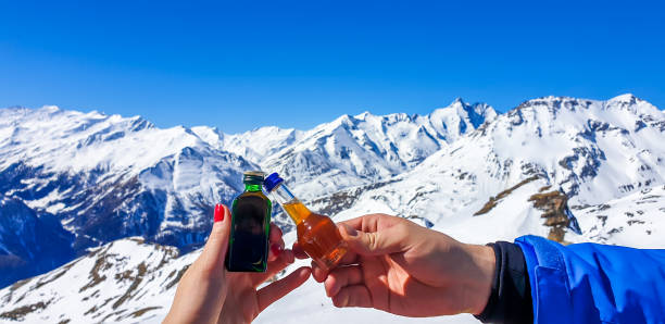 heiligenblut - una pareja sosteniendo unas pequeñas botellas de alcohol con las montañas como telón de fondo - beer ski apres ski snow fotografías e imágenes de stock