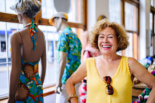 Active senior woman standing in retail shop with hands on hips and smiling at camera during weekend of shopping in Buenos Aires.