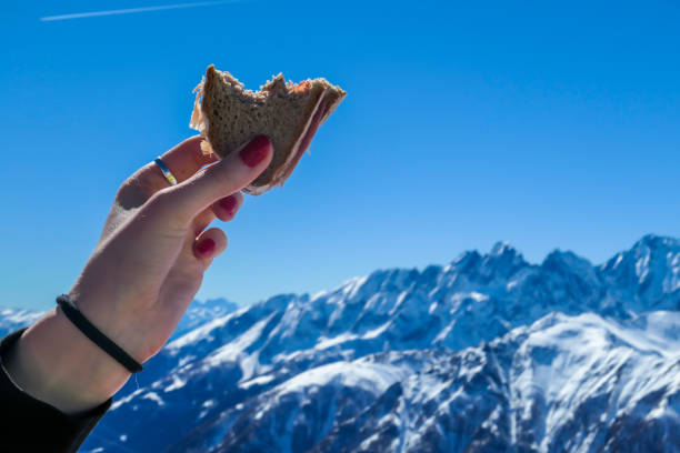 heiligenblut - eine frauenhand hält ein sandwich mit hohen schneebedeckten bergen als kulisse - ski skiing european alps resting stock-fotos und bilder