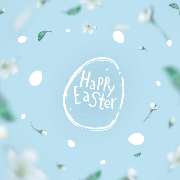 Minimal Easter and spring concept. Lettering Happy Easter in a frame from the flowers of an apple tree on a pastel blue background. Flat lay. Concept - Easter minimalism.