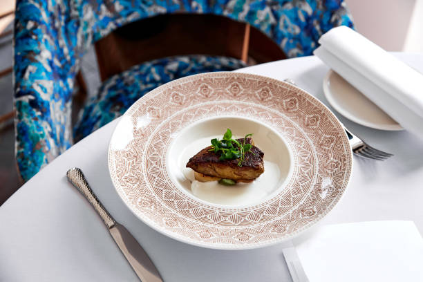 istock Foie gras scallops decorated with greens in sauce on plate with patterns 1211406256
