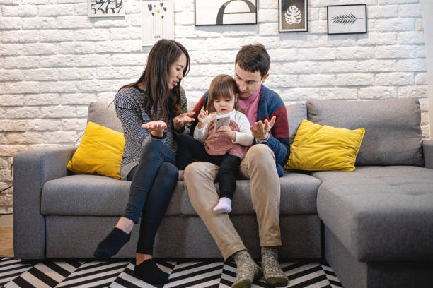 istock Mixed ethnicity family sitting on a sofa with a beautiful daughter 1211406964