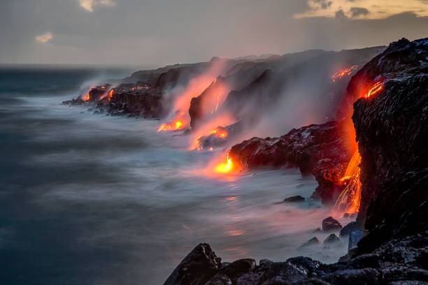 Lava Falls Over Cliff, Big Island, Hawaii A series of lava flows spill into the ocean over a cliff at dusk, on the Big Island, Hawaii hawaii volcanoes national park photos stock pictures, royalty-free photos & images
