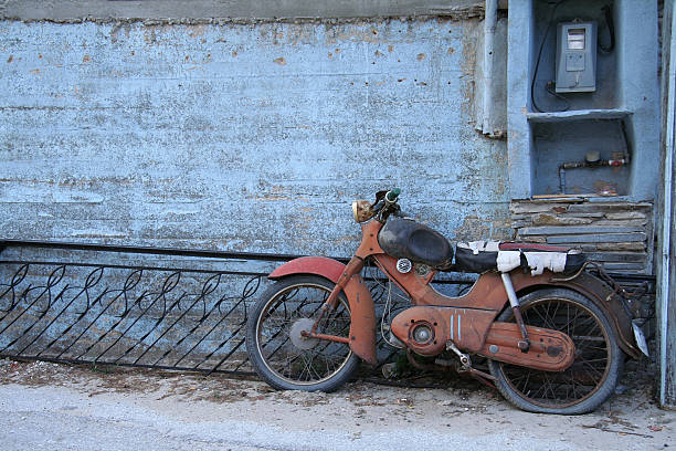 Rusty old  Motorcycle by blue wall in Greece stock photo