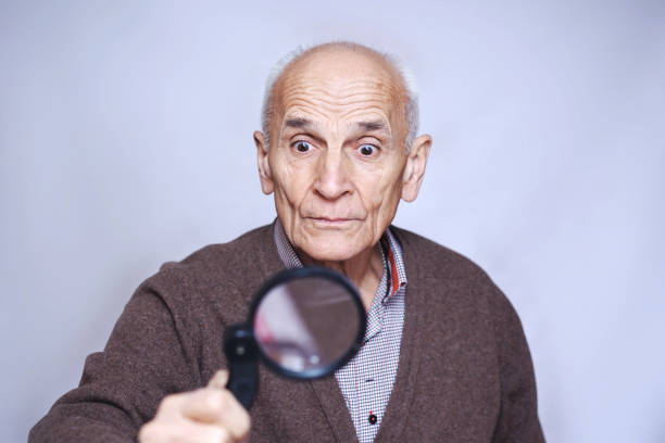 istock old pensioner looks with a magnifying glass 1211413837