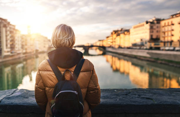 istock Tourist looking at Arno river from Ponte Vecchio in Florence 1211414049