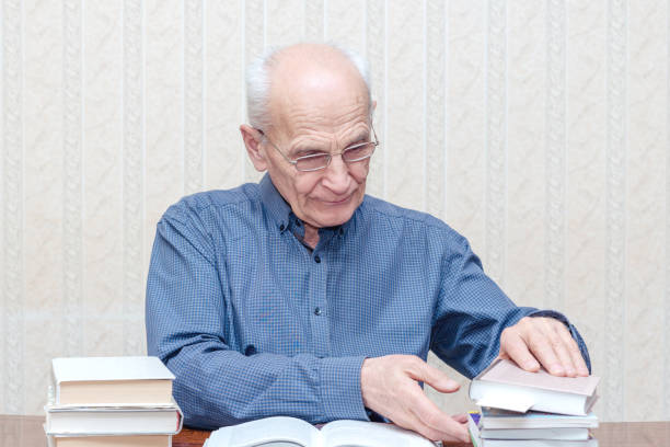 istock Old man considering a pile of books 1211414449