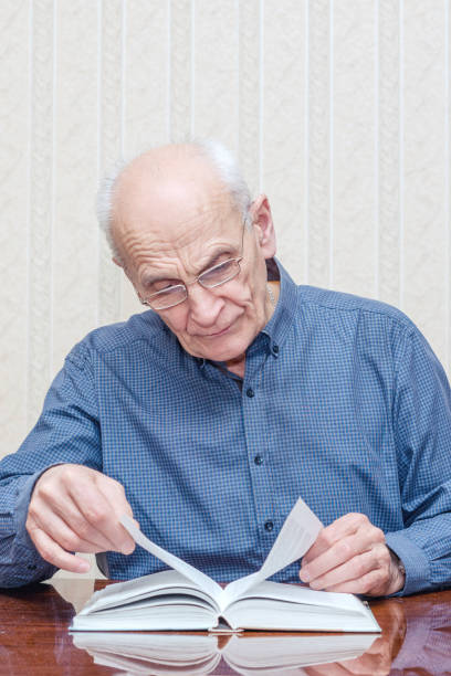 istock old man with glasses reading a book 1211414456