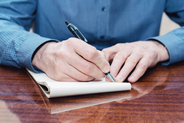 istock hands of the old man at the table with notebook. 1211414482