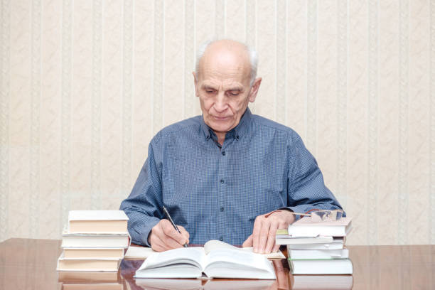 istock Mature professor works at the table 1211414517